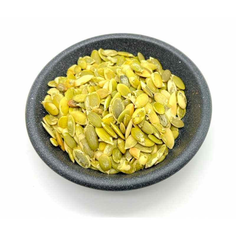 Green pumpkin seeds in a dark bowl